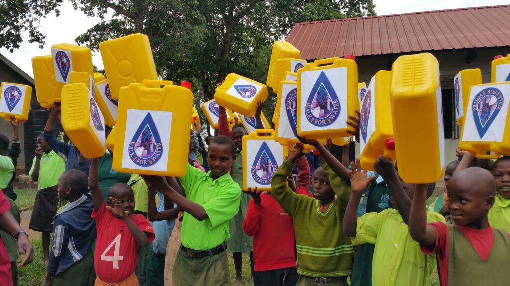 Children holding up water canisters during annual walk for water event Uganda