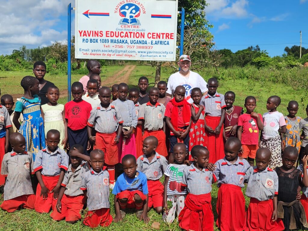 Students gathered around YAVINS Education Centre sign with YAVINS Volunteer Coordinator Tracy Baker